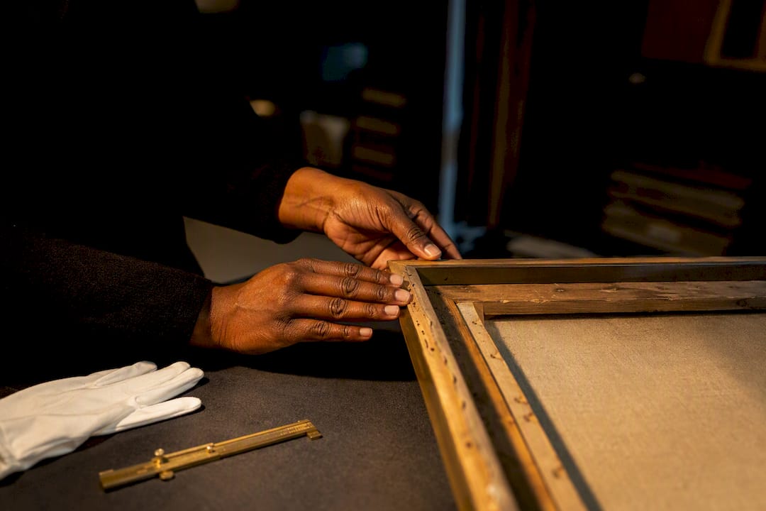 Curator inspecting framed artwork provenance