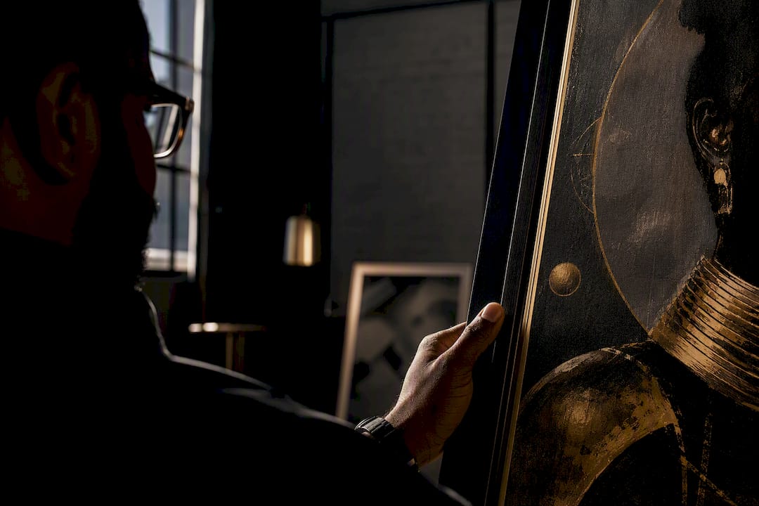 Black collector studying framed artwork at home