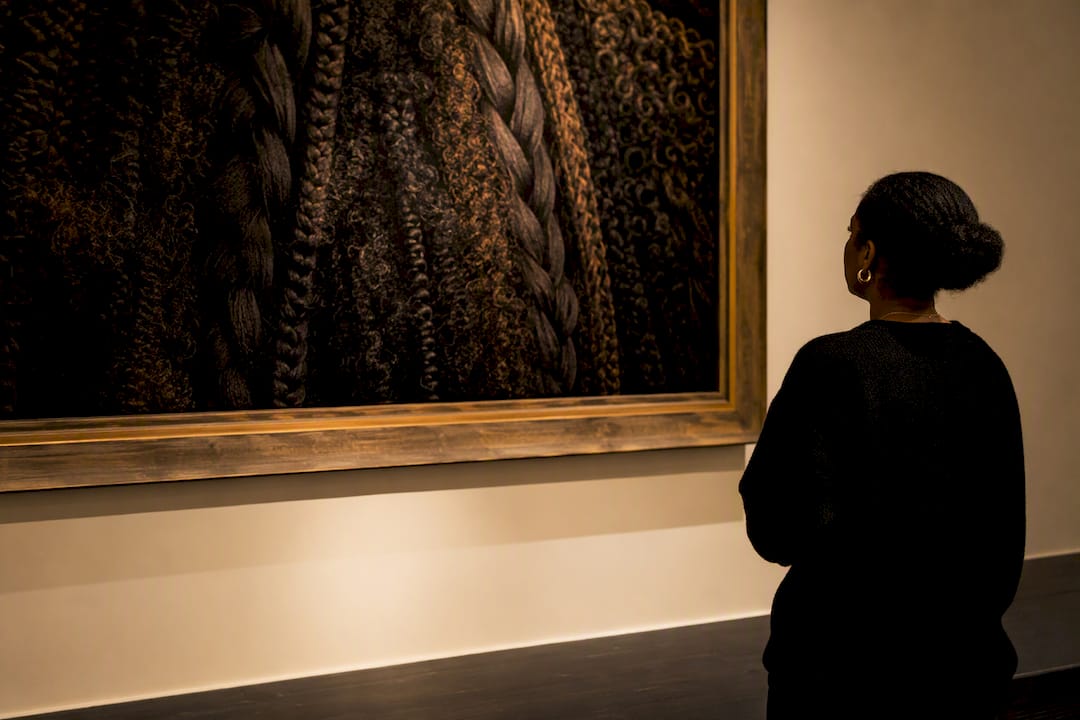 Visitor viewing natural hair artwork in museum