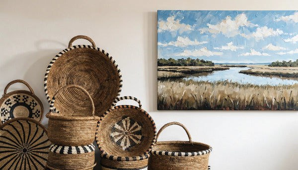 Coiled sweetgrass baskets and a painterly Lowcountry marsh canvas on a warm gallery wall.