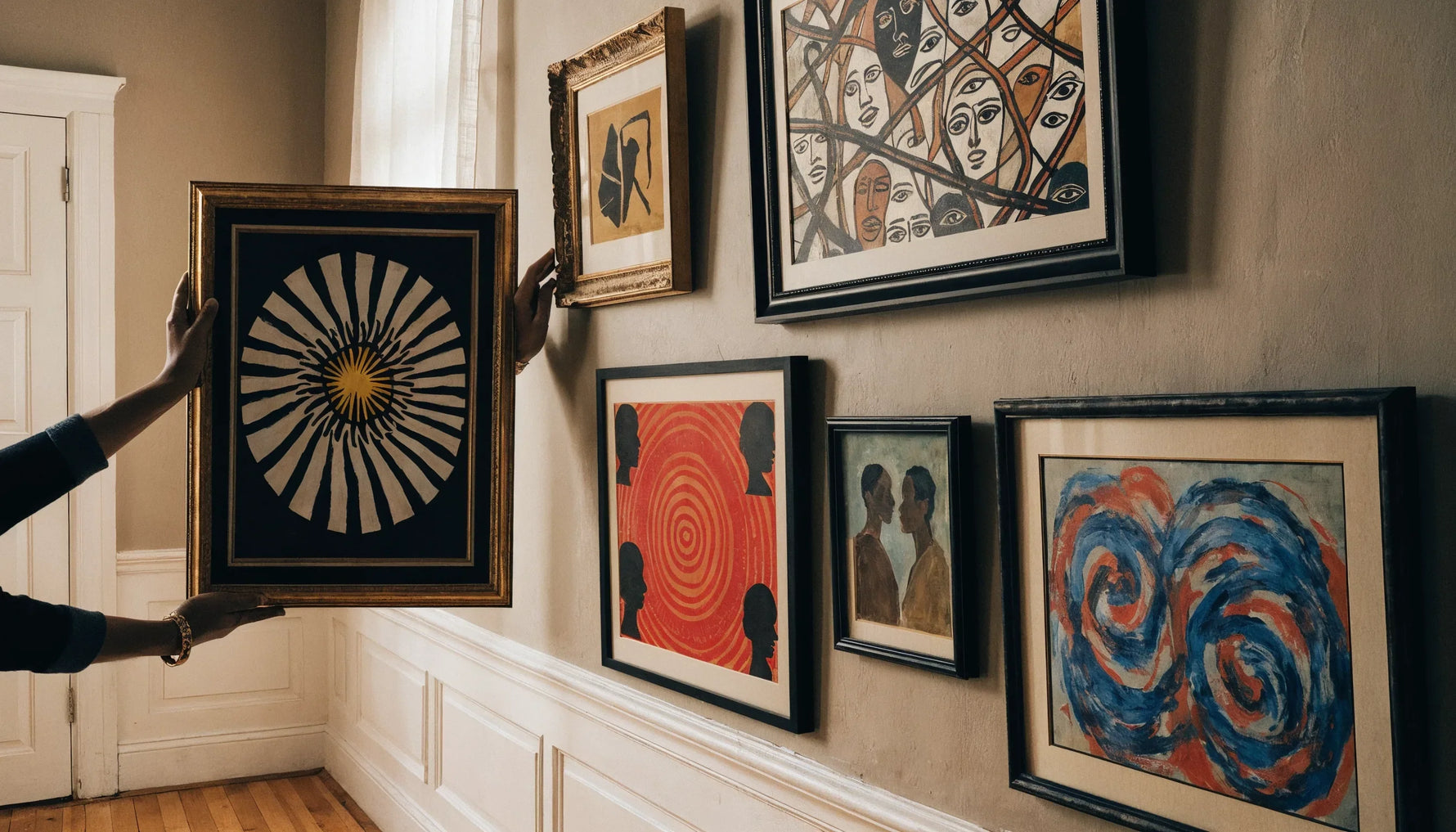 A museum curator's hands arranging framed original Black-art on a gallery wall, thoughtful and careful, no face.