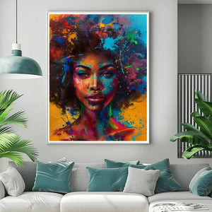 Afrofuturism art in a white frame above a gray sofa with teal pillows, splash-paint portrait of a Black woman with neon afro