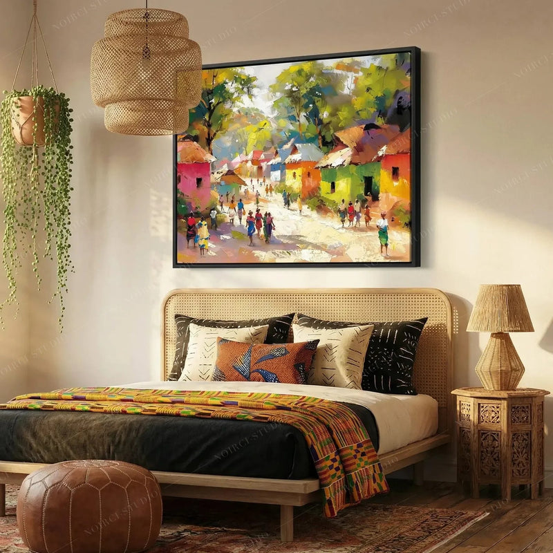 African American art for the bedroom, black-framed village painting above a cane bed with a kente throw
