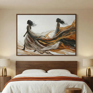 Black women canvas art above a walnut platform bed, two figures in flowing gowns trailing amber and charcoal fabric