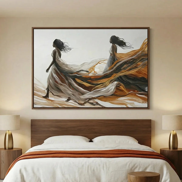Black women canvas art above a walnut platform bed, two figures in flowing gowns trailing amber and charcoal fabric