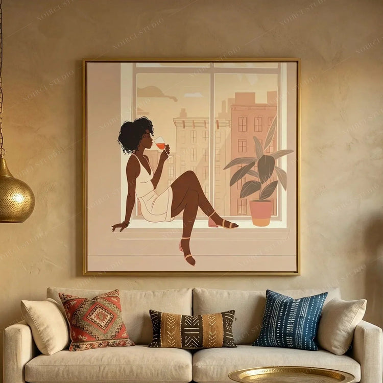 Black woman wine art in a gold frame above a beige sofa with kilim and mudcloth pillows, woman sipping wine at a city window