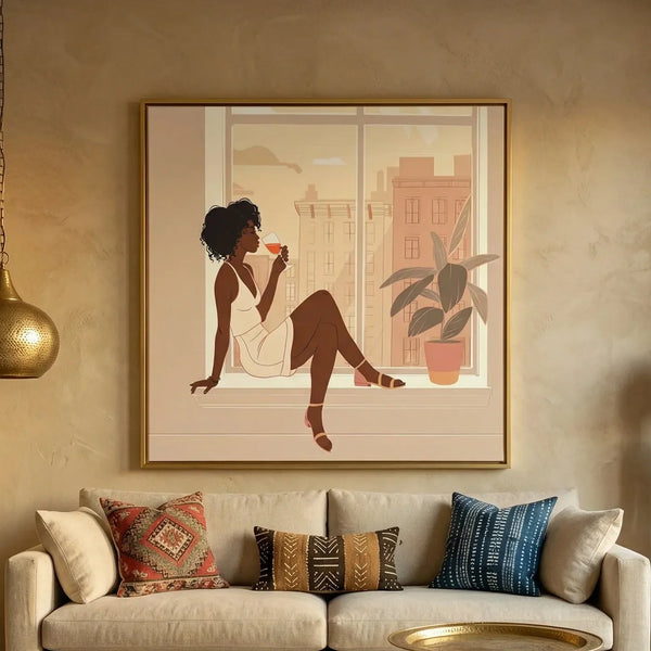 Black woman wine art in a gold frame above a beige sofa with kilim and mudcloth pillows, woman sipping wine at a city window
