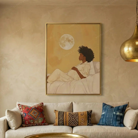 Black maternity wall art above a cream sofa with mudcloth pillows, pregnant Black woman resting under a full moon