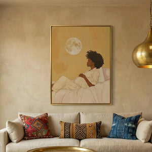 Black maternity wall art above a cream sofa with mudcloth pillows, pregnant Black woman resting under a full moon