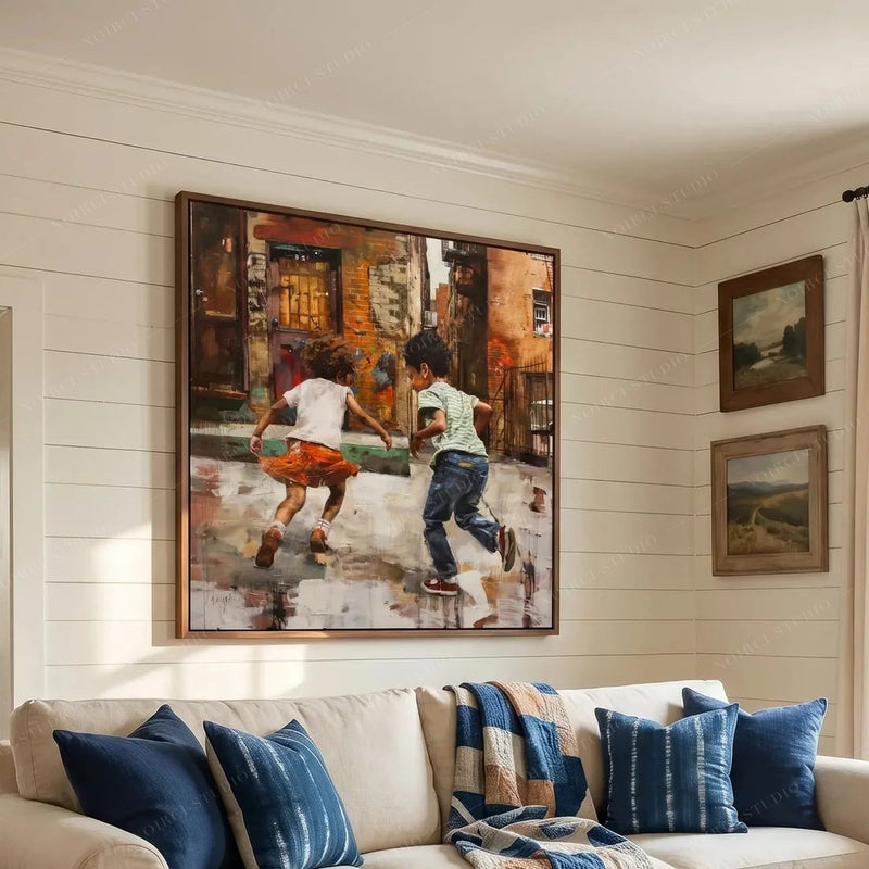 Black art for living room walls, kids running scene in a walnut frame above a cream sofa with indigo pillows