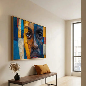 Black entryway art, mosaic man portrait in a gold frame above a bench with an ochre pillow by a tall window