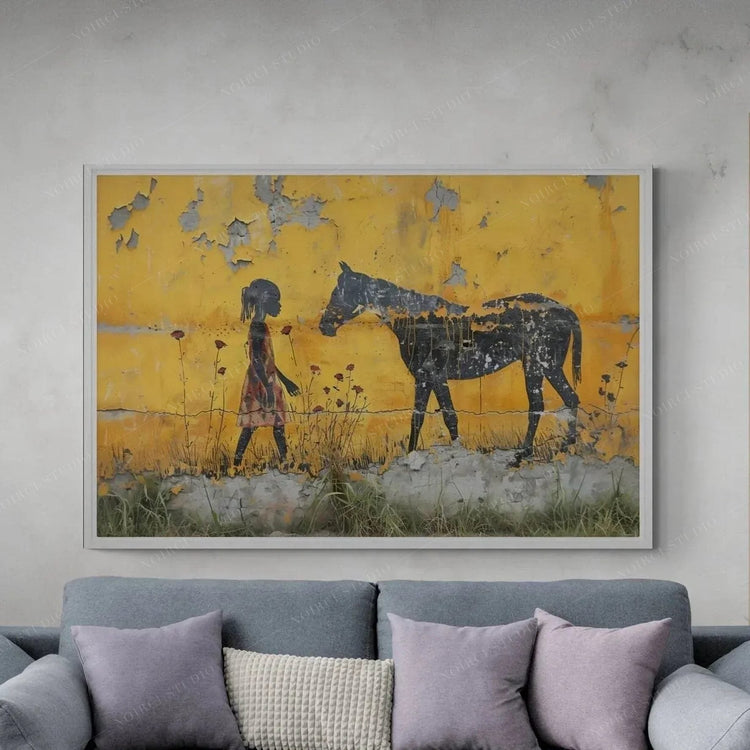Afrohemian wall art above a gray sectional, Black girl offering a rose to a horse on a peeling yellow wall