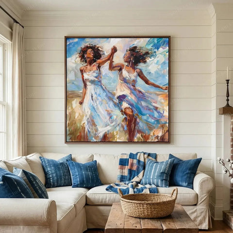 Black women dancing wall art in a shiplap living room above a cream sofa with indigo pillows, friends twirling in sundresses