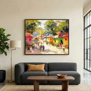 African landscape painting in a black frame above a dark gray sofa, colorful village scene with figures on a sunlit path