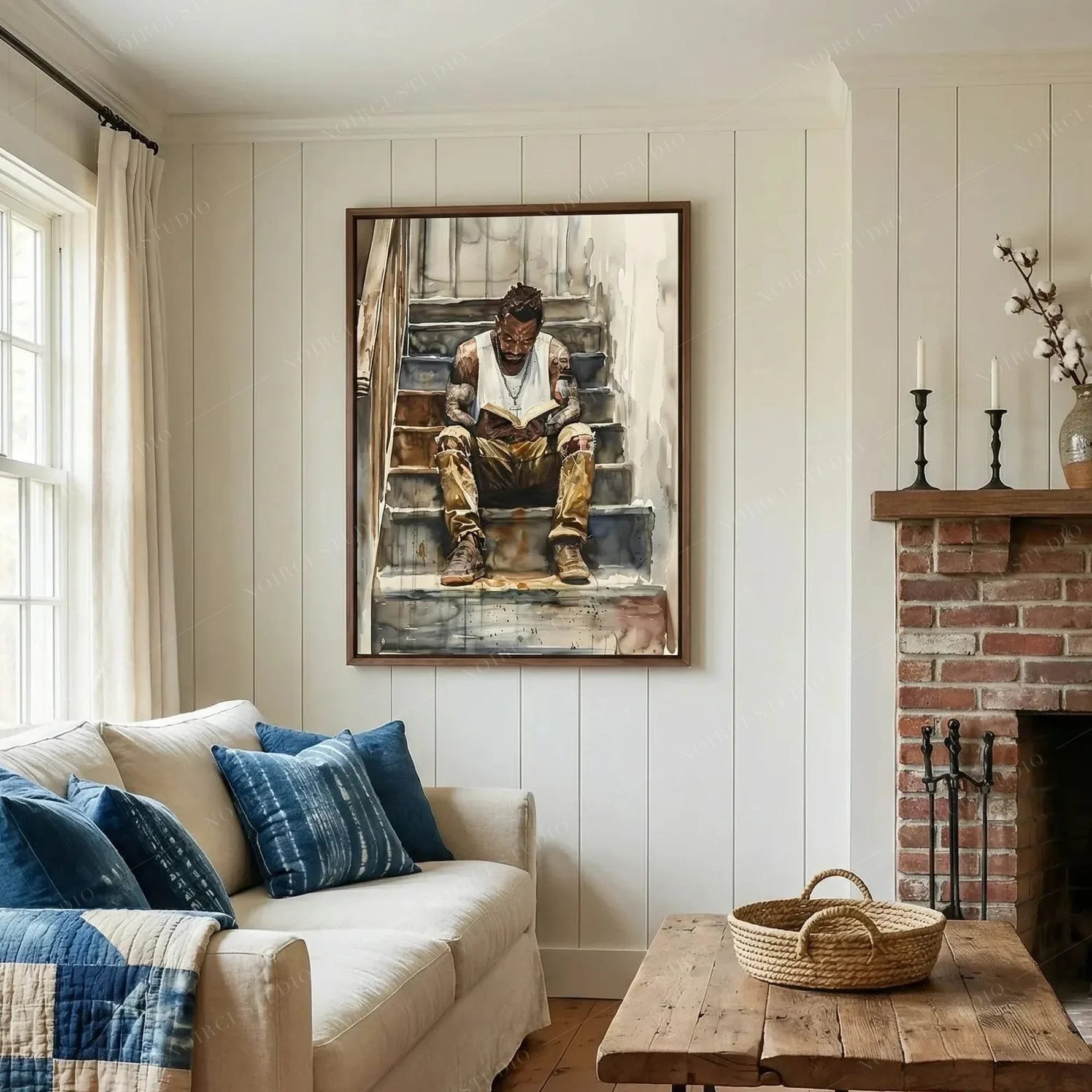 African American wall art in a shiplap living room with brick fireplace and blue pillows, man reading watercolor