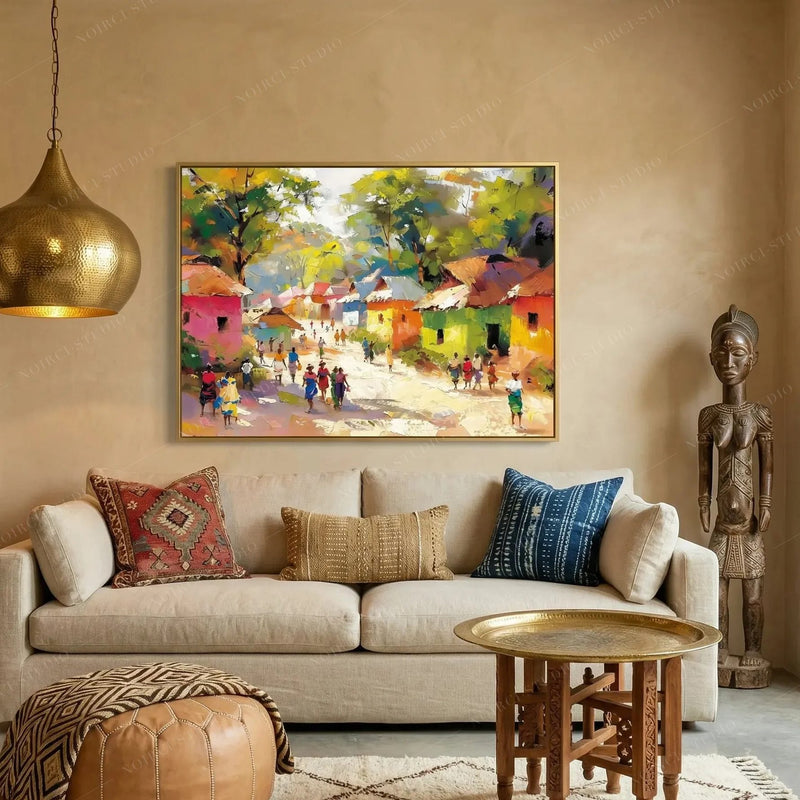 African wall art for living room, village scene in a gold frame above a cream sofa with kilim and indigo pillows