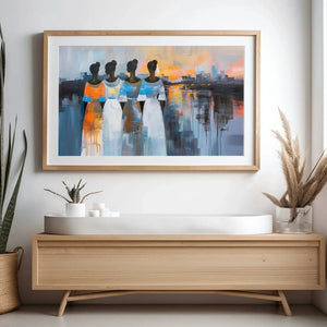 African American wall art, four Black women at a harbor sunset, oak framed above a light wood console with snake plant