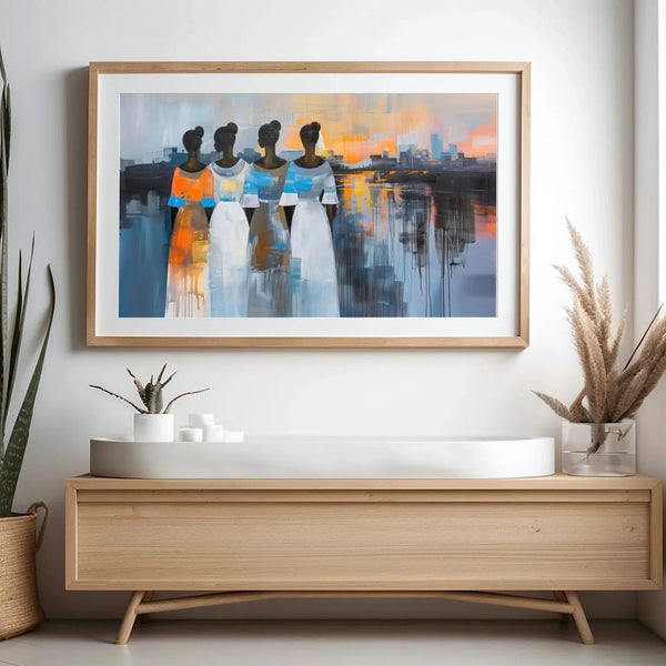 African American wall art, four Black women at a harbor sunset, oak framed above a light wood console with snake plant