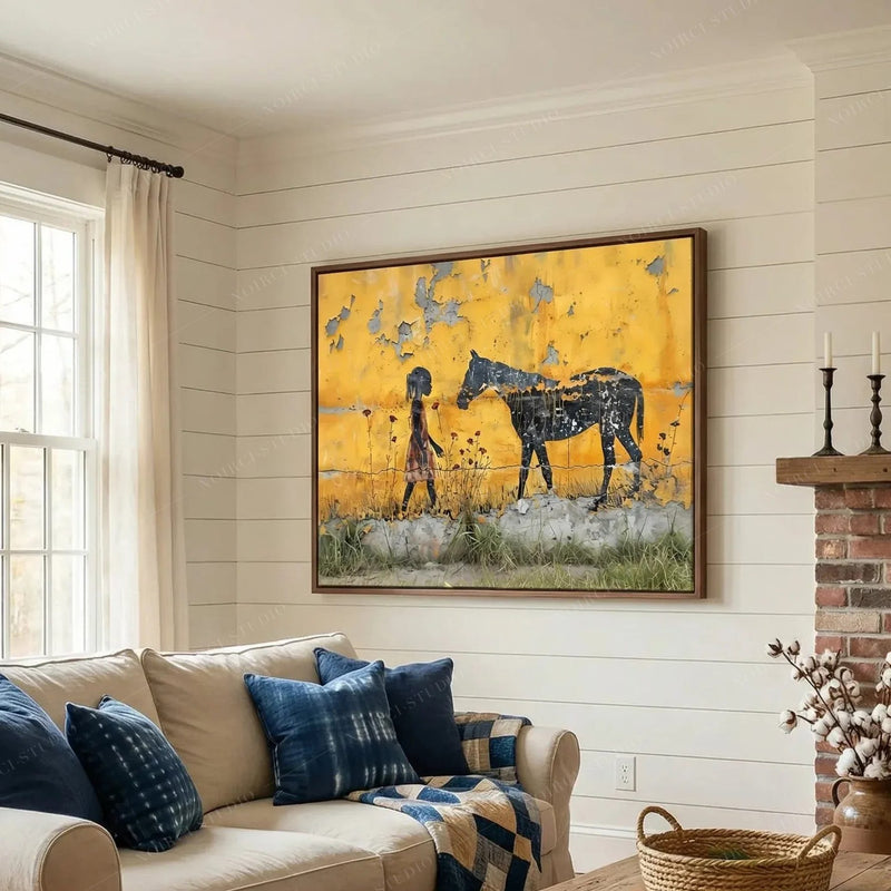 Black art for living room, framed girl and horse scene above a cream sofa with indigo pillows near a brick fireplace