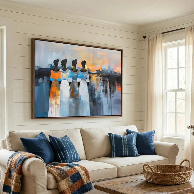 African art for a farmhouse living room, four Black women at sunset above a cream sofa with navy mudcloth pillows